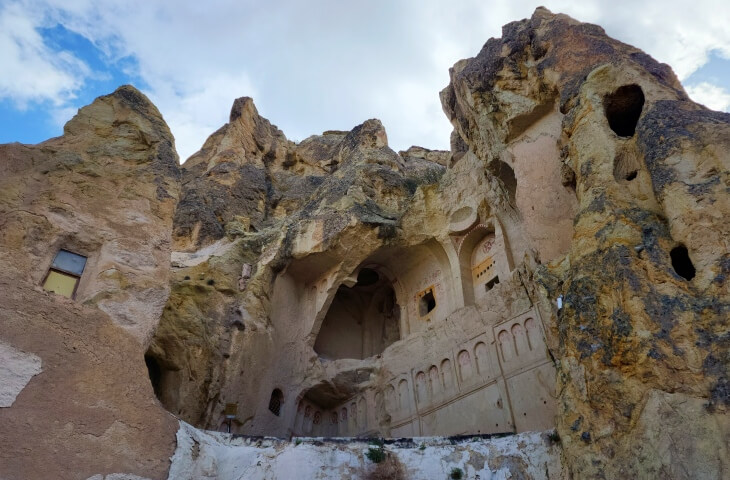 Göreme Açık Hava Müzesi’nde bulunan Karanlık Kilise’nin dış cephesi, kayalara oyulmuş kemerli ve işlemeli mimarisiyle yukarıdan aşağıya kadar detaylı şekilde görülüyor.